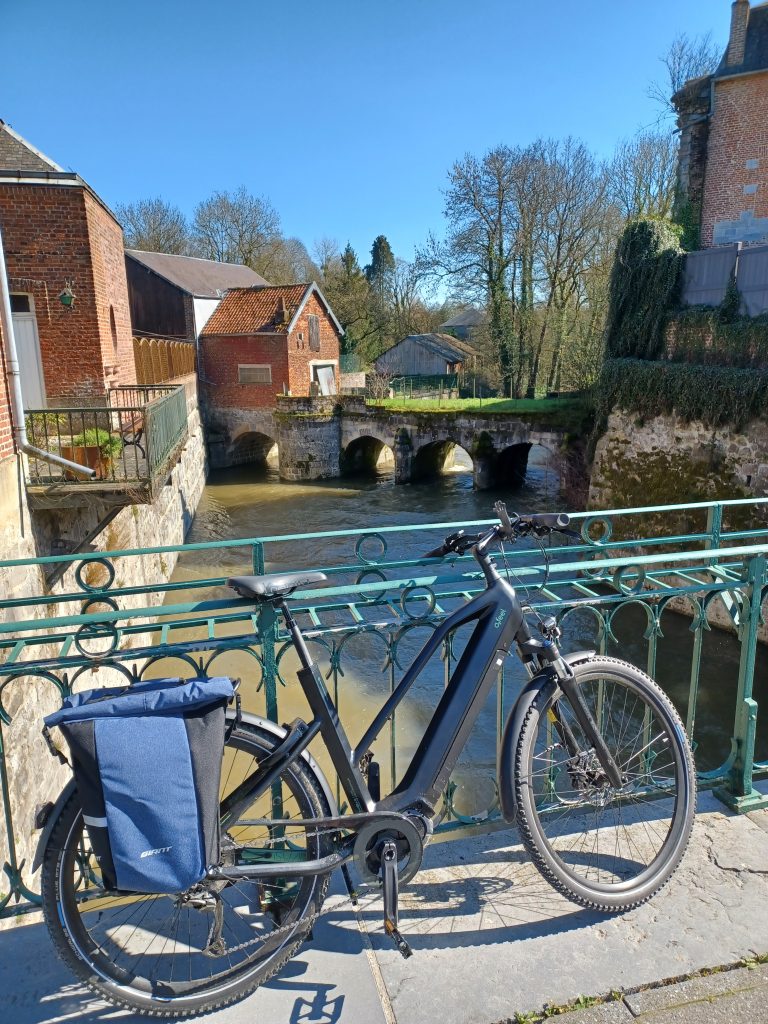 Vélo à assistance électrique posé sur une barrière près d'un ruisseau 