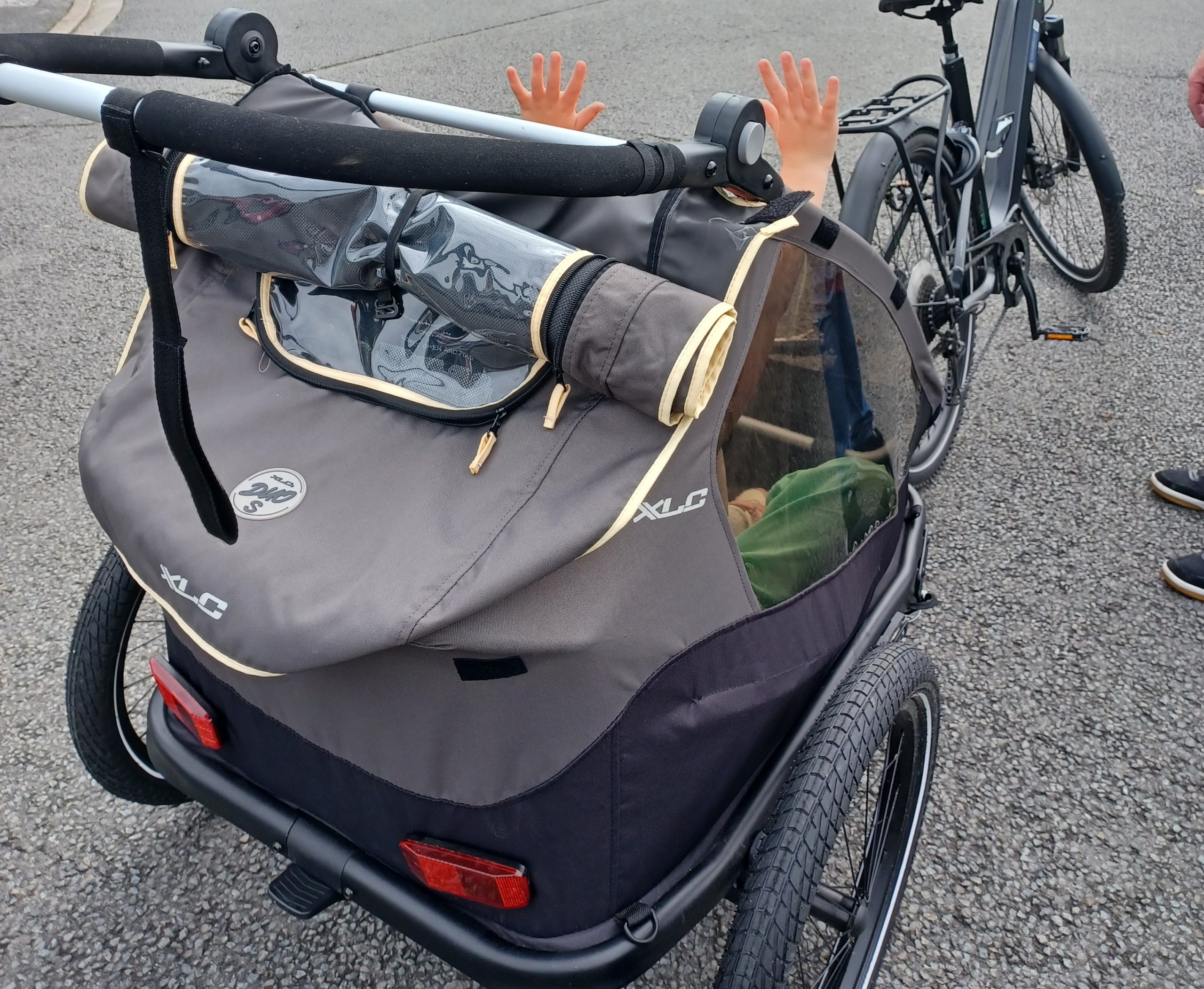 Charrette vue de dos sur la route avec des mains en l'air d'enfabnts. Attachée à un VAE